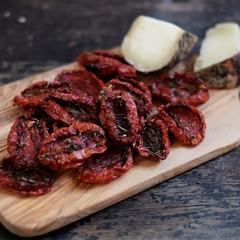cheese on a wooden board with dried tomatoes