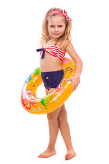 Beautiful little girl in red striped bikini, blue bottoms and pink wreath stand stand with colorful rubber ring on the waist