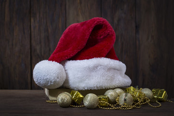 Obraz na płótnie Canvas Santa Claus hat, a book, golden decorative boxes, balls and beads. Focus on the Santa Claus hat