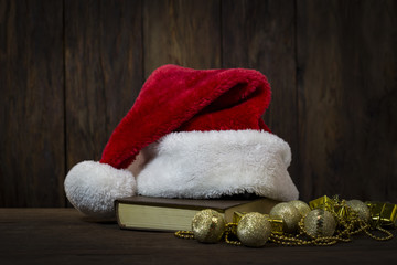 Obraz na płótnie Canvas Santa Claus hat, book, decorative boxes, beads and beads. Focus on the Santa Claus hat
