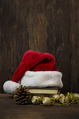 Obraz na płótnie Canvas Santa Claus hat, two books, a cone, decorative boxes, balls and beads. Focus on the Santa Claus hat
