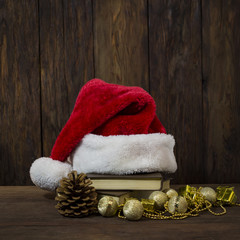 Obraz na płótnie Canvas Santa Claus hat, books, fir cone, decorative boxes, beads and beads. Focus on the Santa Claus hat