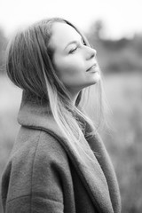portrait of a lonely girl in a coat that looks into the distance. black and white photo