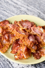 Crisp fried bacon on the plate above grey granite background table