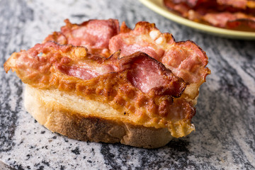 Crisp fried bacon on the bread above grey granite background