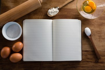Book, eggs, flour, spoon and rolling pin kept on a table © wavebreak3