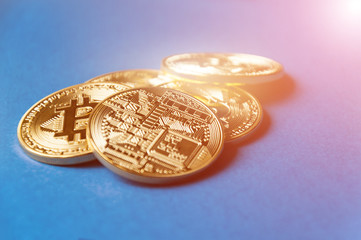 Several coins of bitcoins lie on a blue background with bright glow, toning and blurring. Crypto...