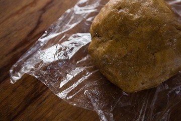 Dough placed over plastic wrap on a wooden table