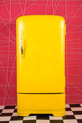 old vintage yellow refrigerator on a pink background