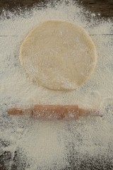 Flattened dough sprinkled with flour on a wooden table