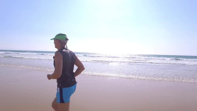 Adult Man in Shorts with a T-shirt Jogging on Ocean Beach, close up POV
