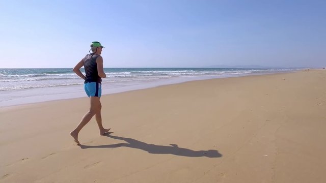 Adult Man in Shorts with a T-shirt Jogging on Ocean Beach, close up POV
