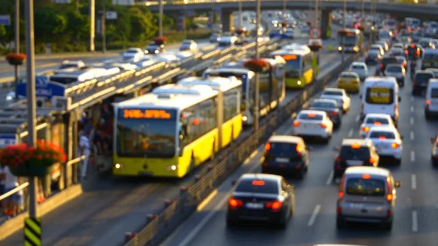 Insane rush hour traffic jam in Istanbul Metro Bus Line. High speed public buses moving on express way. Incirli bus stop with yellow buses. Out of focus.