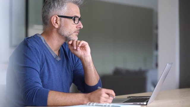 Middle-aged man working from home-office on laptop