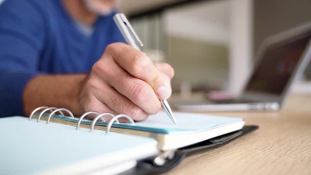 Closeup of man writing in agenda