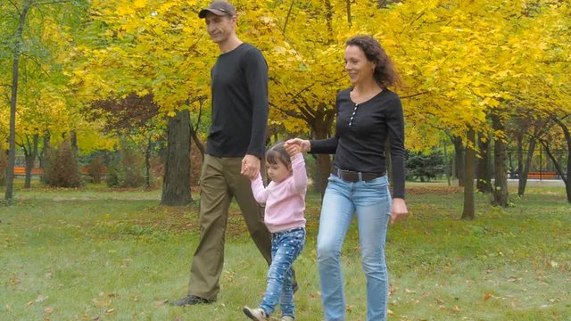 Happy family in autumn park. Parents with the child walk in the park.