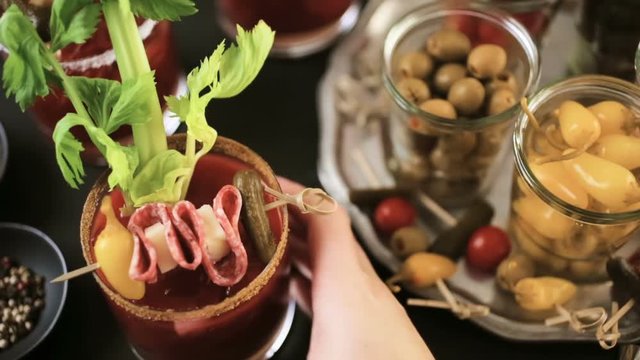 Bloody mary cocktail garnished with celery sticks, olives, and bacon strips