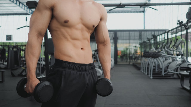 Strength fitness body shirtless muscular man lifting weights in sport gym, blurred image for healthy lifestyle background