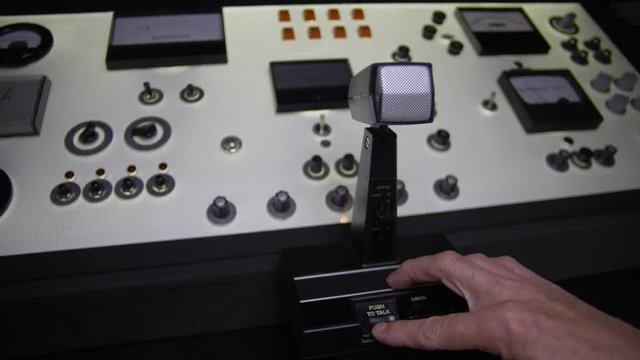 BROADCASTING CONSOLE.  Hand ativates a microphone.