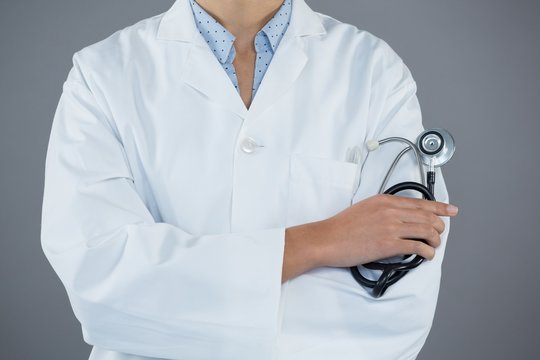Doctor holding stethoscope against grey background