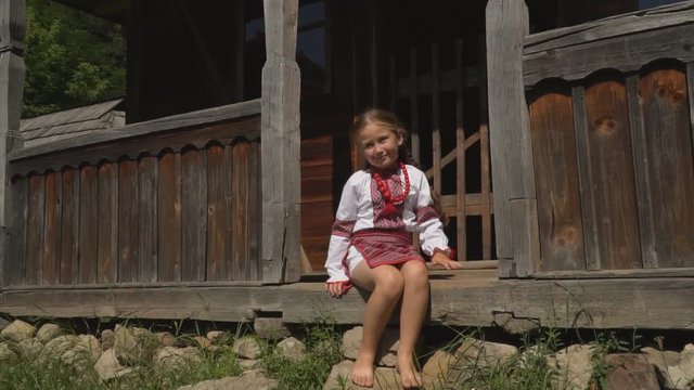 little girl is sitting on the porch of the house