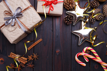 Christmas composition with gift boxes, candies, baubles and decorations on dark wooden background. Christmas eve, New year celebration concept