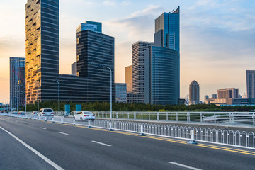 Naklejka premium Empty urban road and modern skyline at dusk