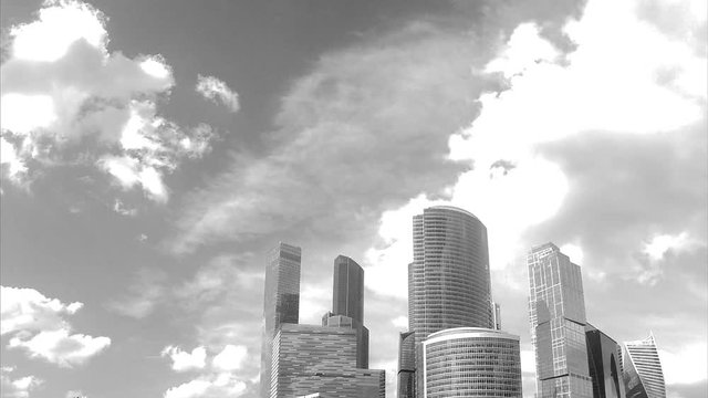 different glass towers and sky with clouds black and white timelapse