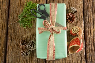 Fototapeta na wymiar Scissors, pine cones, leaves and ribbon with wrapped gift box on