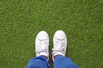White canvas leather shoes on green lawn.