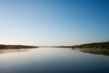 Fishing boat on foggy autumn river.