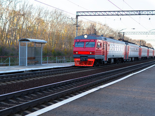 Red Train locomotive coming to platform Station. Passengers on the right.