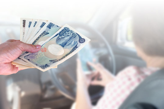 closeup hand woman with Japanese currency yen bank notes on blurred background senior woman driving car and using cellphone, maintenance cost of car concept