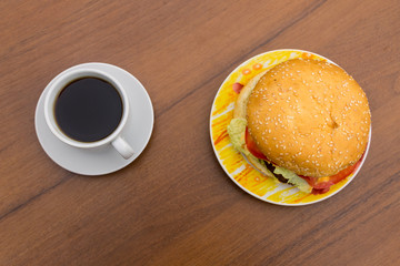 Delicious hamburger and cup of coffee on wooden table