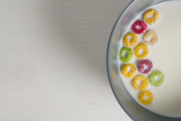 Bowl of milk and cereal rings on white background