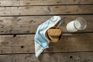 Granola bar and milk with napkin on wooden table