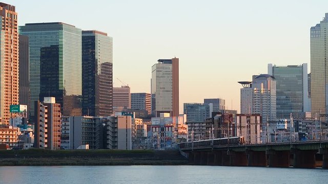 夕暮れの淀川を渡る阪急電車と大阪キタのビル群（4倍速）