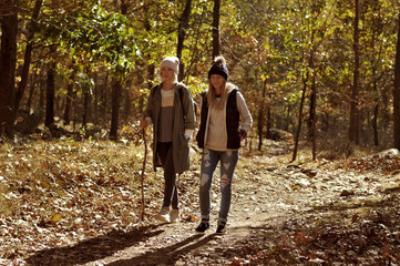 Fototapeta premium Girls walking in autumn forest in the mountains. Hiking and traveling