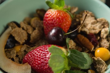 Bowl of breakfast cereals with fruits on black background
