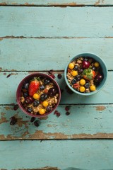 Bowls of breakfast cereals with fruits on wooden table
