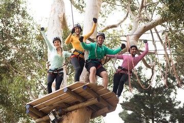 Friends enjoying zip line adventure in park - Powered by Adobe