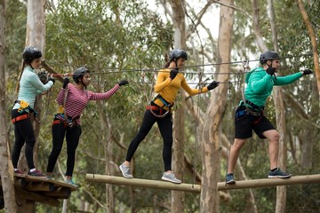Friends enjoying zip line adventure in park