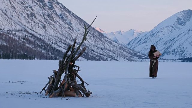 Monks in brown cloaks of the order of St. Franciscarries wood to the fire