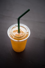 Orange juice  in a plastic glass placed on a wooden table.