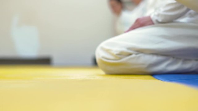 in kimono sitting on tatami of martial arts.