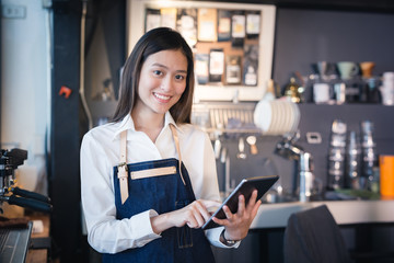 Asian woman barista smiling with tablet in her hand,Female employees are taking orders from online customers