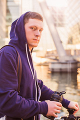 Portrait of young sporty man who standing outdoor and holding bottle in hand
