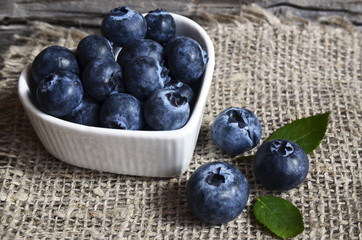 Freshly picked blueberries in a white heart shaped bowl on old wooden background.
Fresh organic blueberry.Bilberries.Healthy eating,vegan diet or raw food concept.Selective focus.