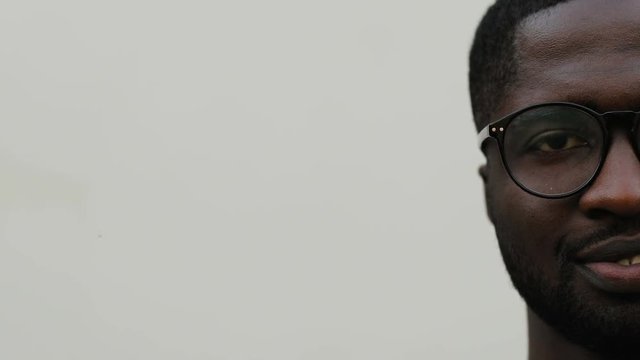 Right half of face of guy in glasses on white background. Young African man looking at camera. Close-up.