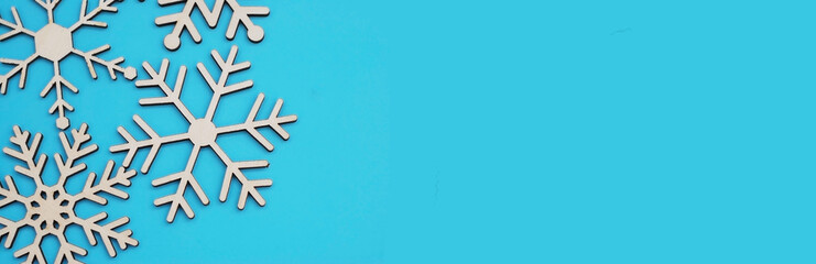 Wooden snowflakes laser cut in the corneron blue background. Flat lay and top view. Banner size.